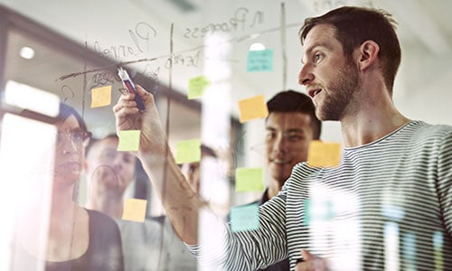 Junger Mann erklärt etwas an einer Glasscheibe